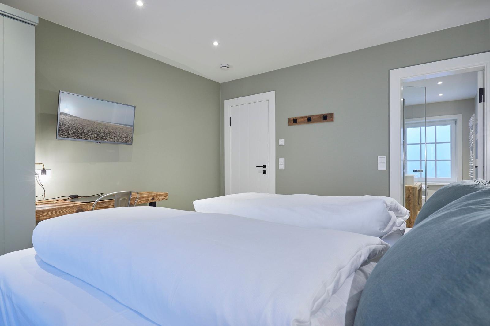 Zimmer mit zwei Betten, Fernseher und Blick in das Badezimmer.