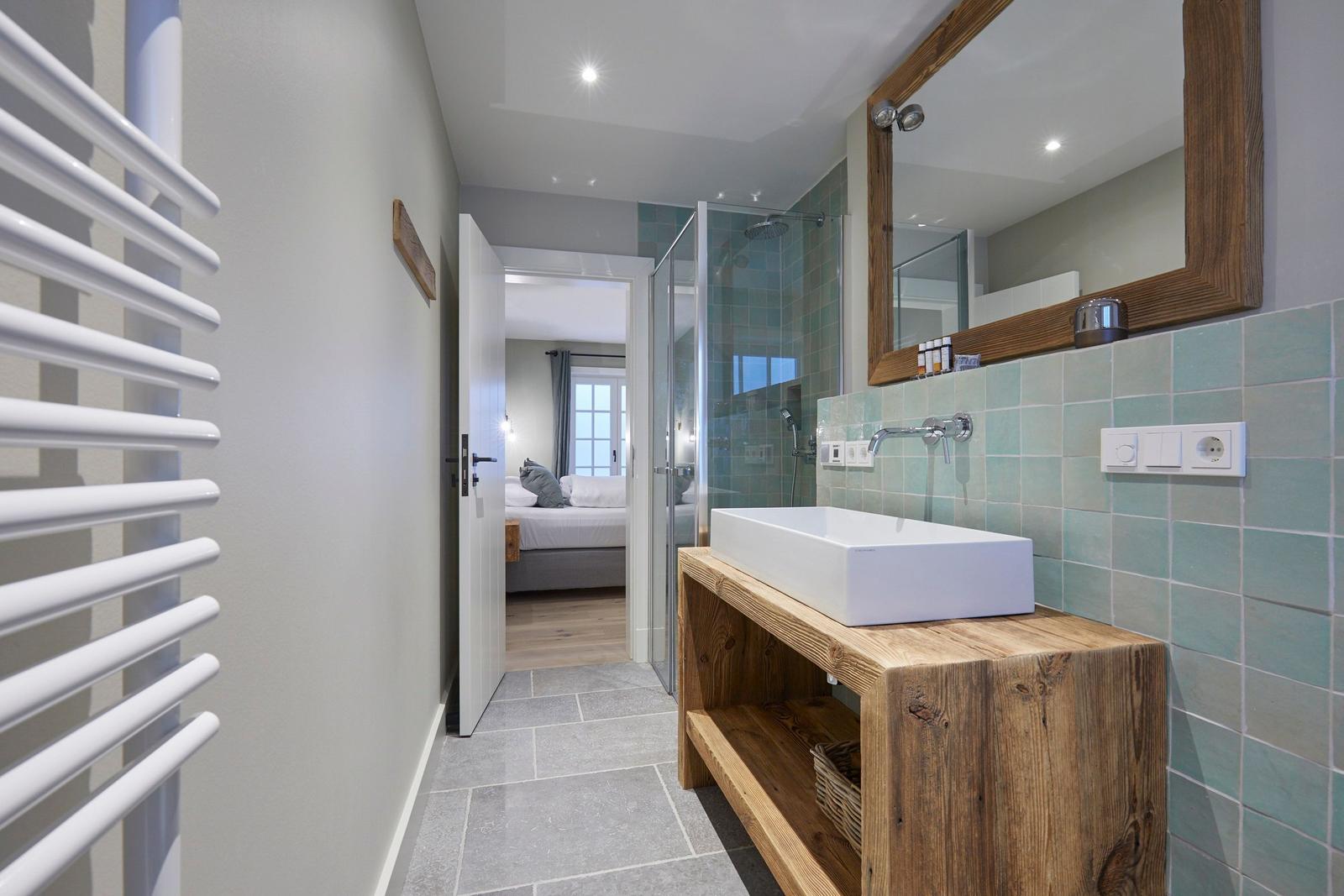 Badezimmer mit Waschbecken, Dusche und Blick in Schlafzimmer