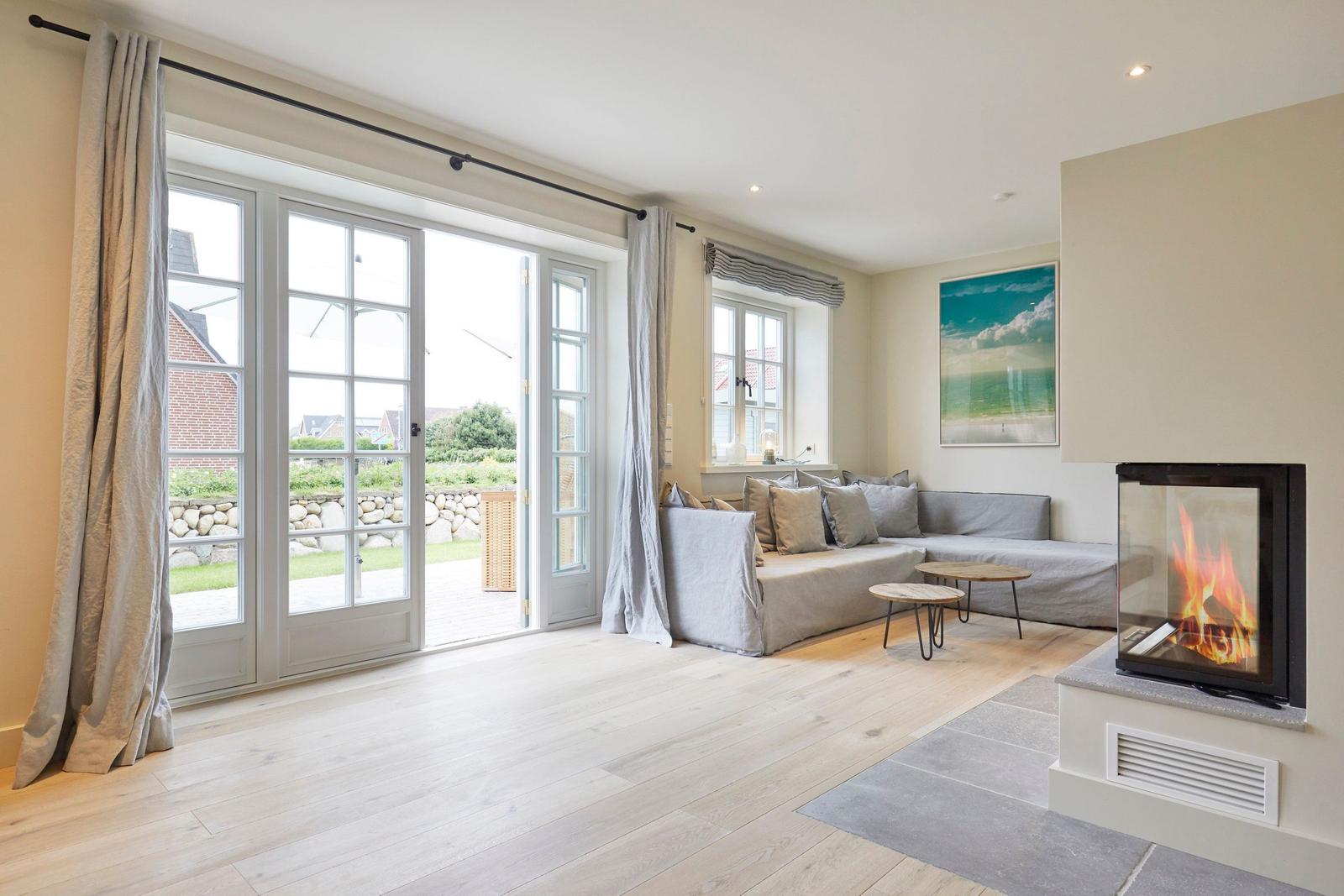 Wohnzimmer mit Kamin, Sofa und Fenster zur Terrasse.