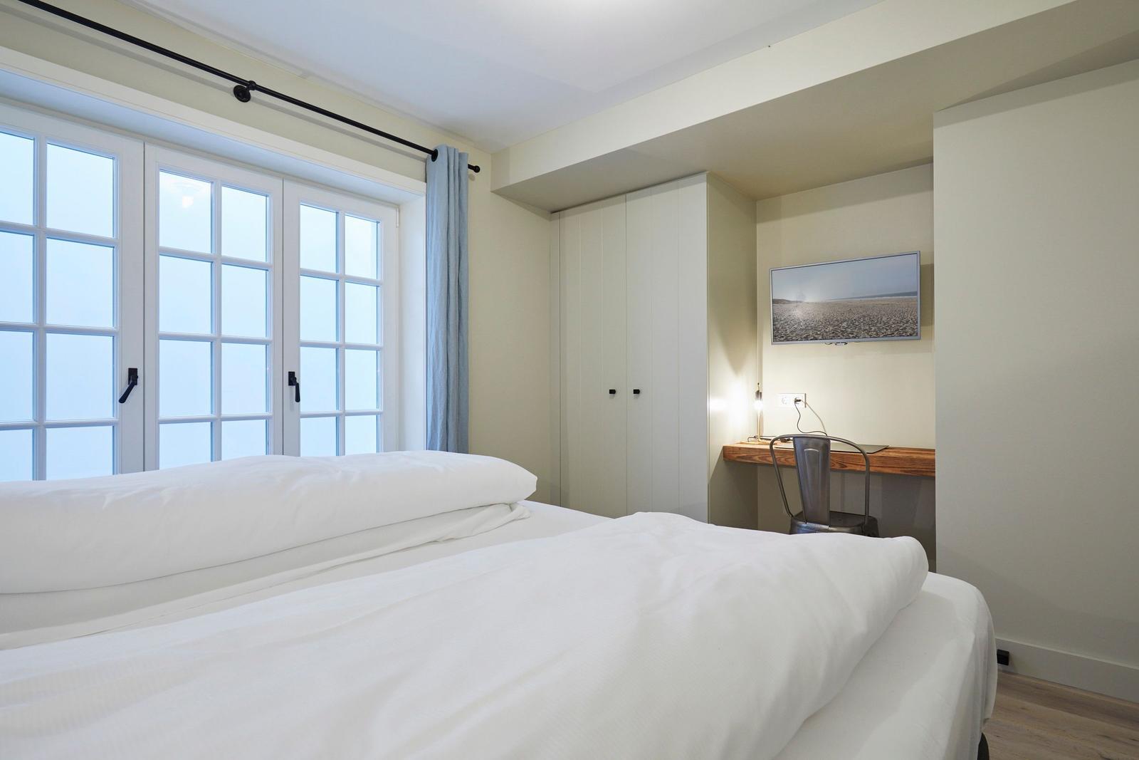Schlafzimmer mit Doppelbett, Fenster und Schreibtisch