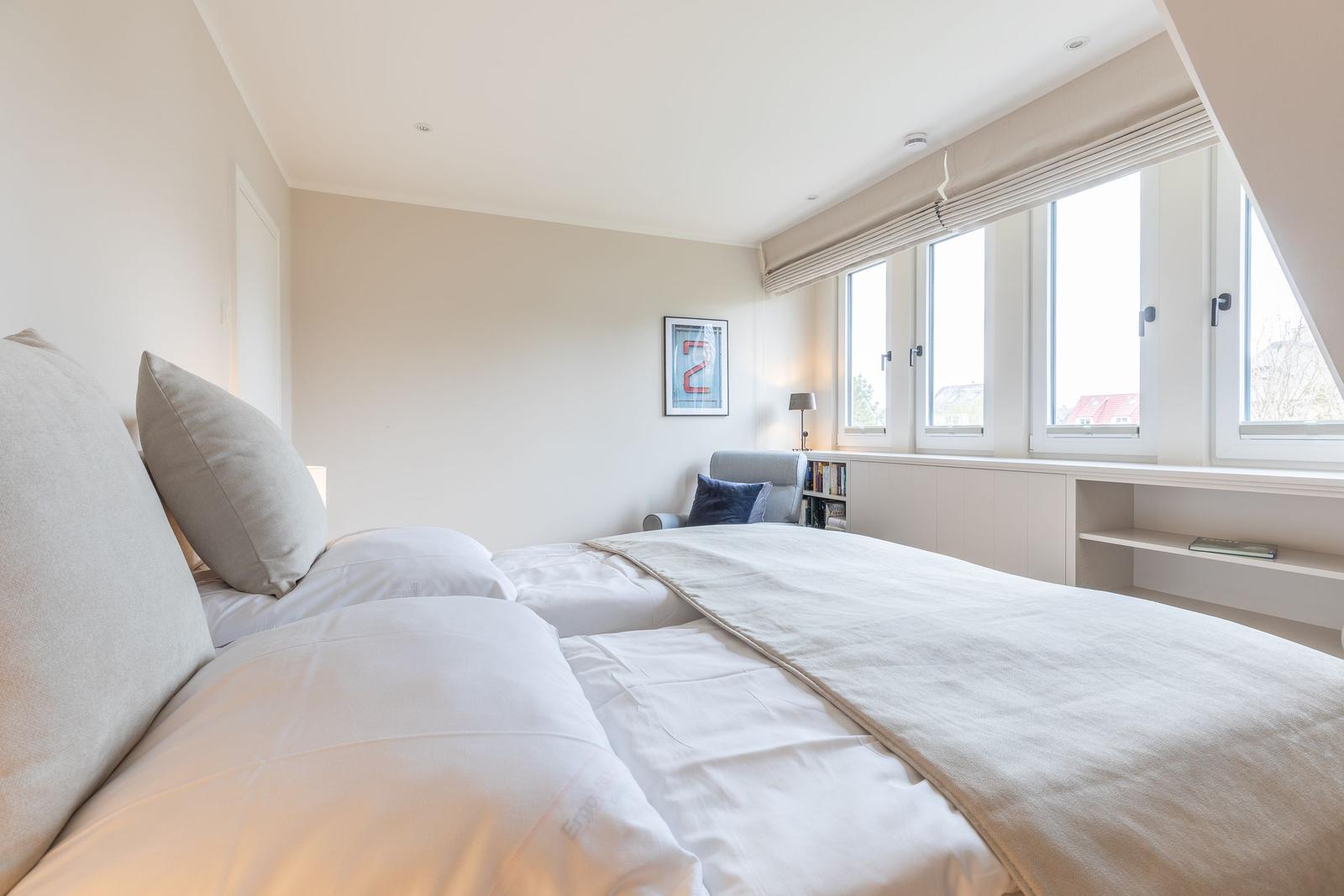 Schlafzimmer mit Bett, Fenster und Sitzgelegenheit