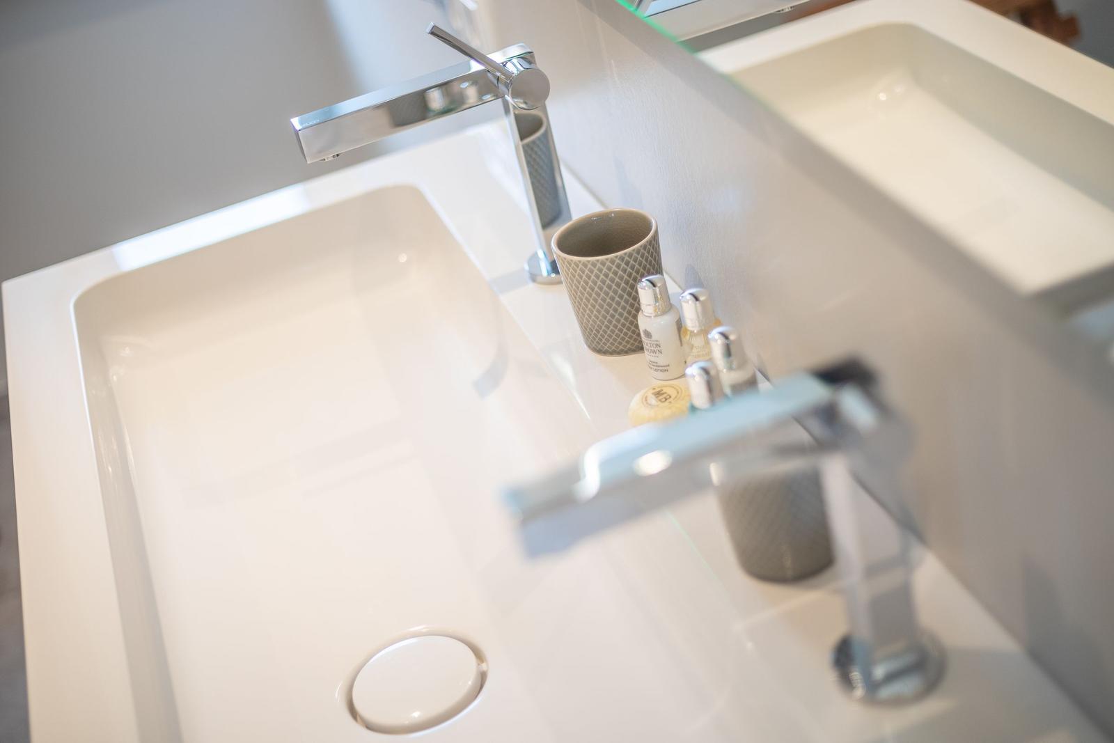 Hochwertige Waschbecken mit modernen Wasserhähnen und Pflegeprodukten.