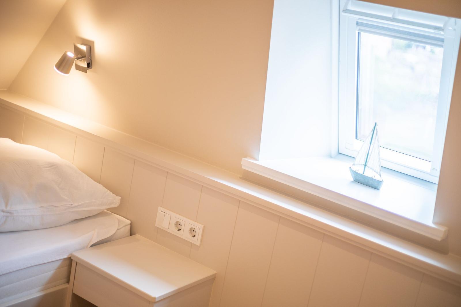 Schlafzimmer mit Bett, Nachttisch und Fenster mit Segelboot.