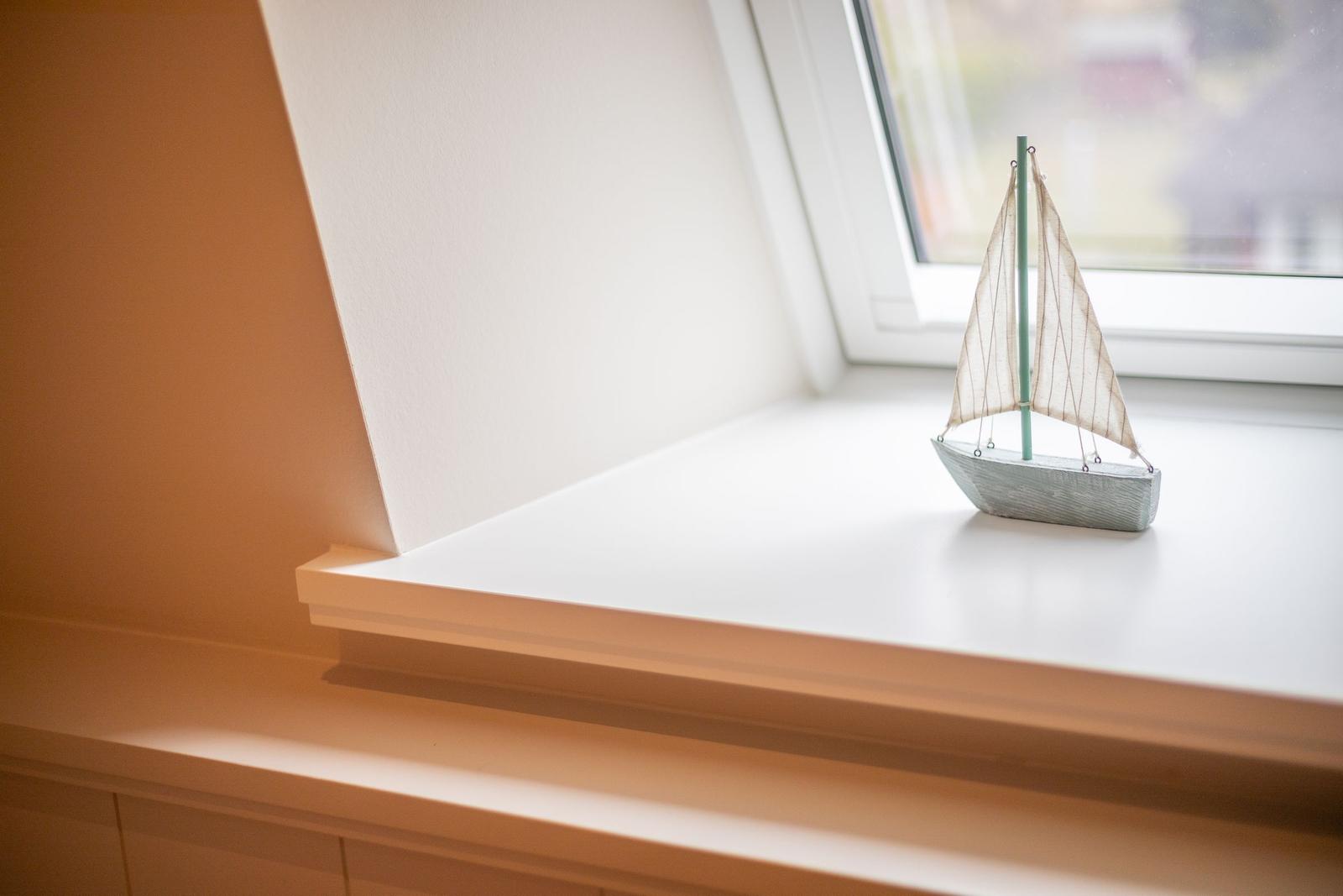 Ein Segelschiffmodell steht auf einem Fensterbrett. Draußen ist es hell.