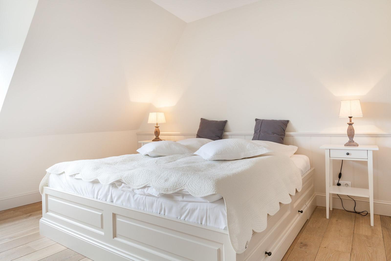 Bedroom with white bed, two nightstands, and lamps.