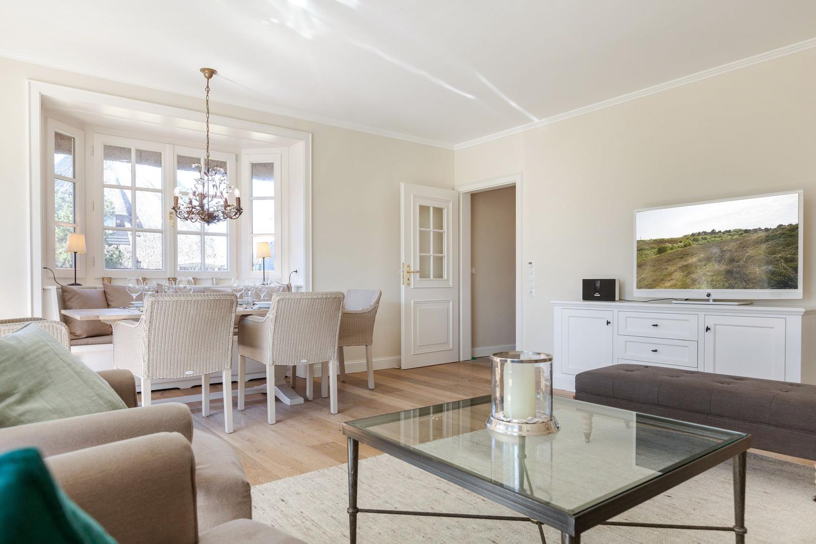 Living and dining area with TV, table and chairs, and glass-top table.