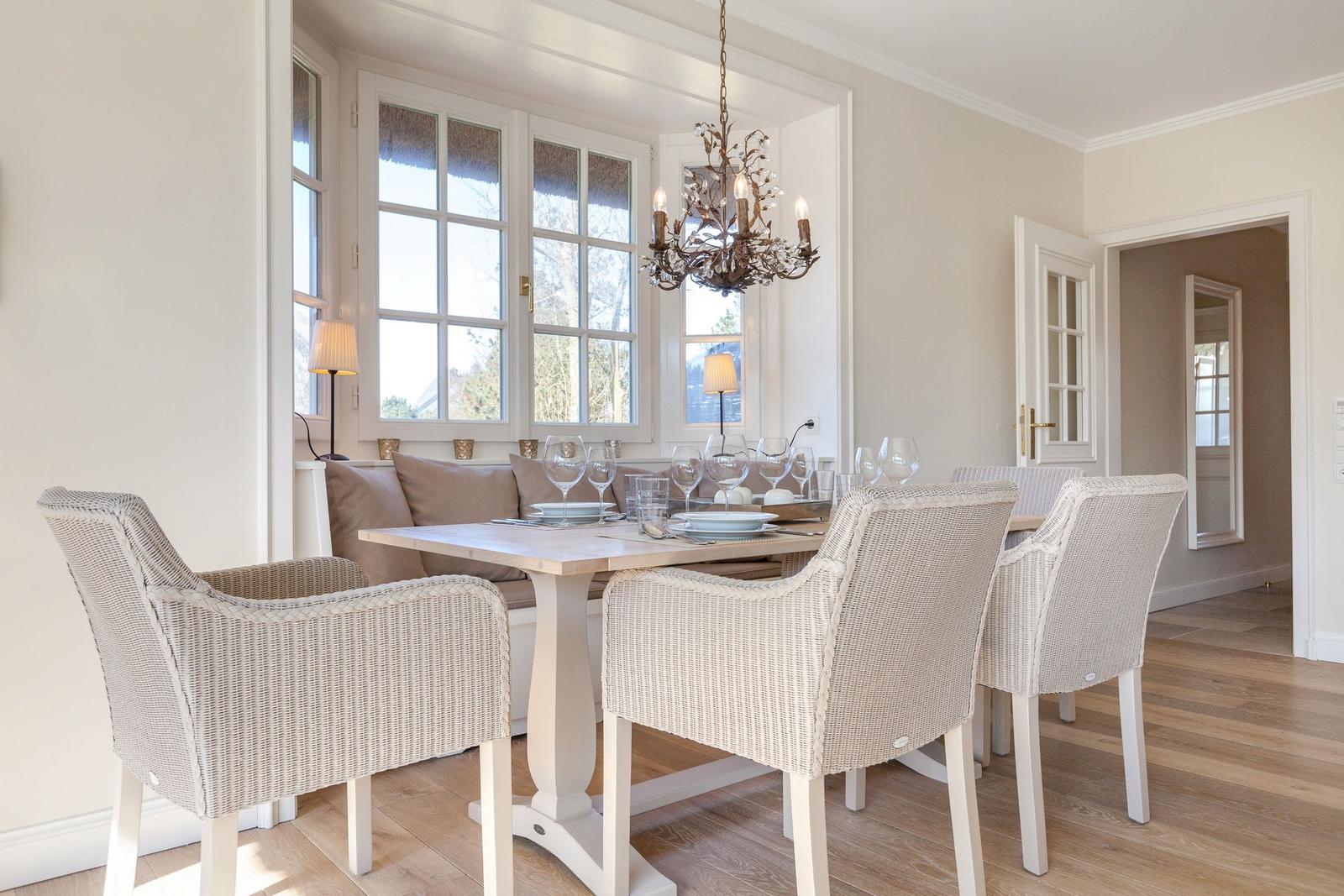 Dining room with table, chairs, and windows. Ceiling light and wooden floor.