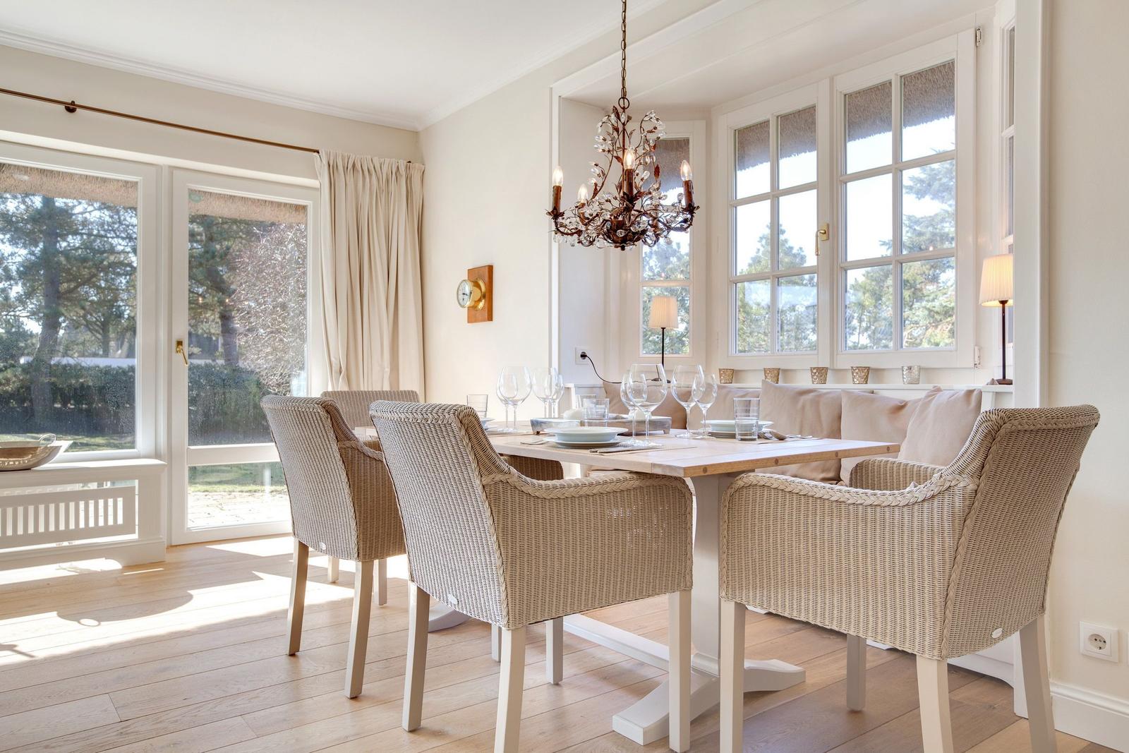 Dining room with table, chairs, and windows. Chandelier and wooden floor.