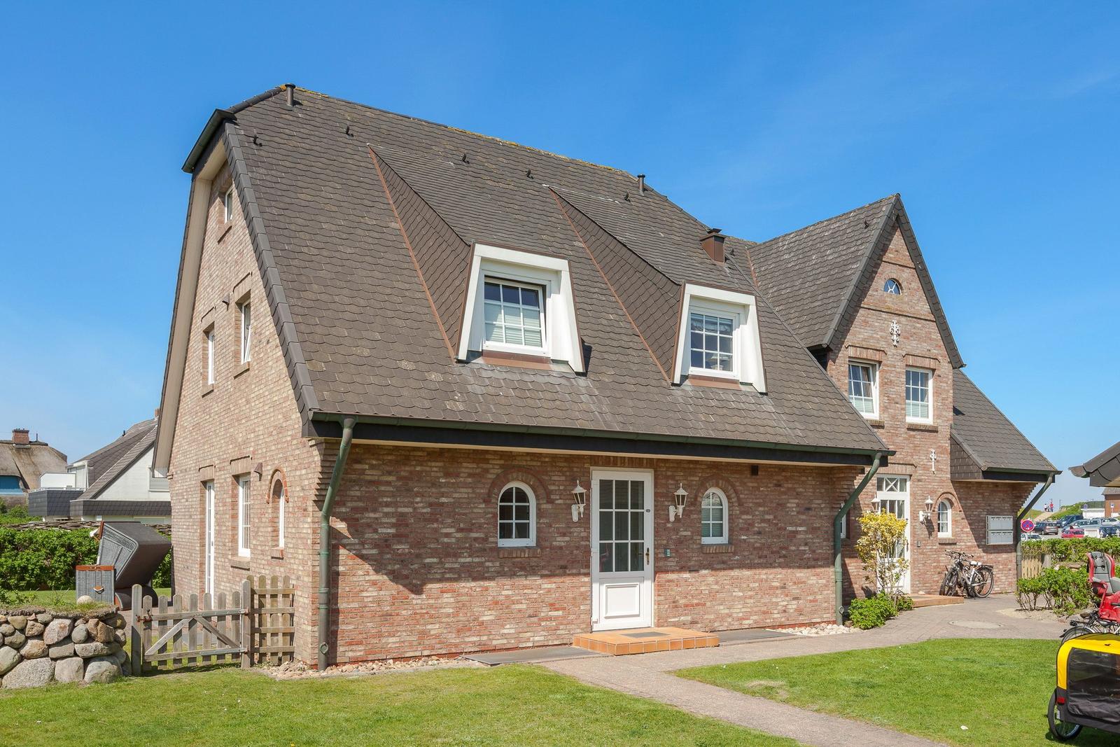 Ein zweistöckiges Haus mit rotem Ziegelmauerwerk und schwarzem Dach.