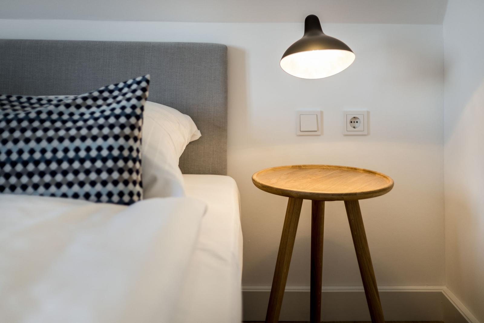 Bedroom with bed, nightstand, and wall lamp.