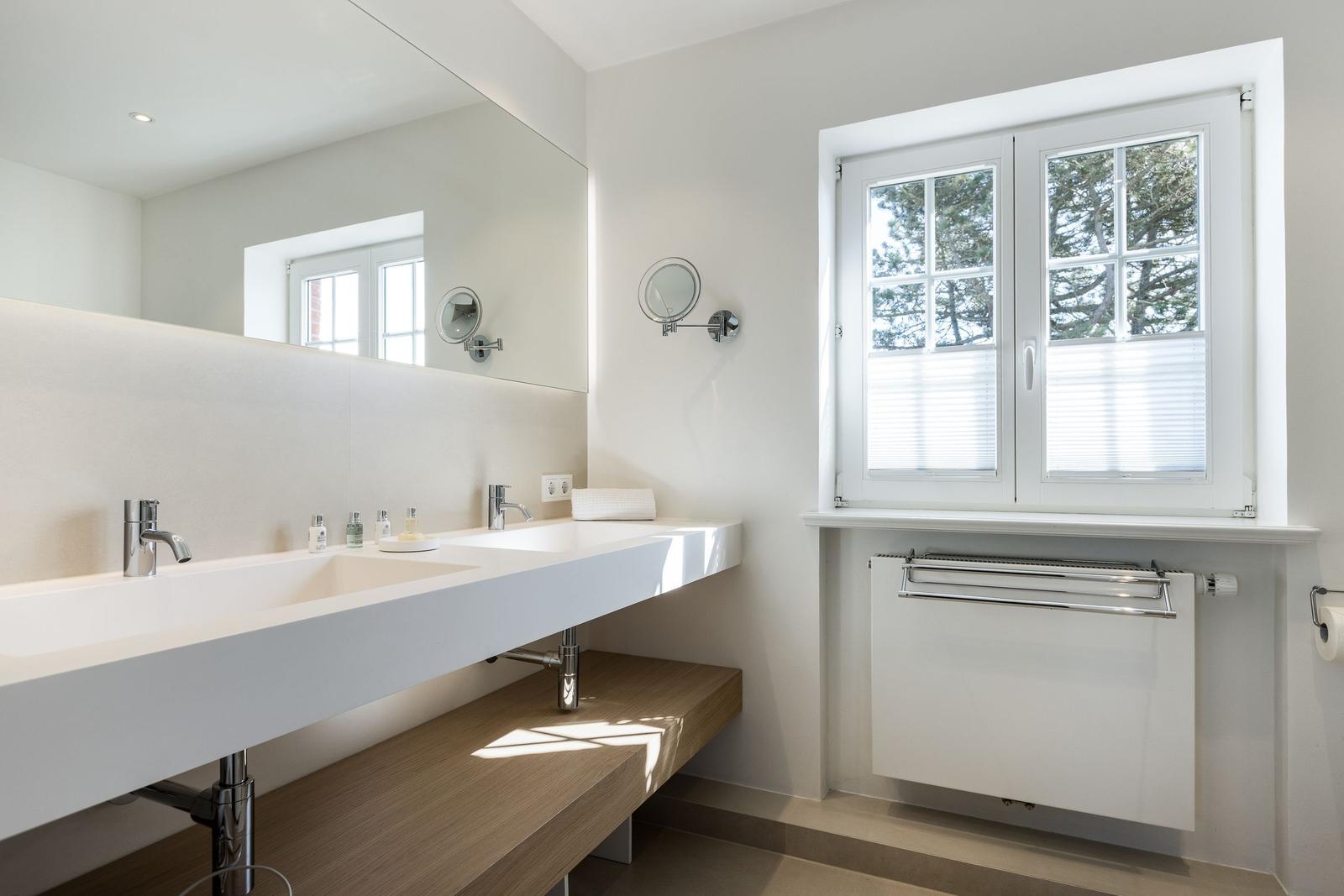 Bathroom with sink, mirror, and window with view of trees.