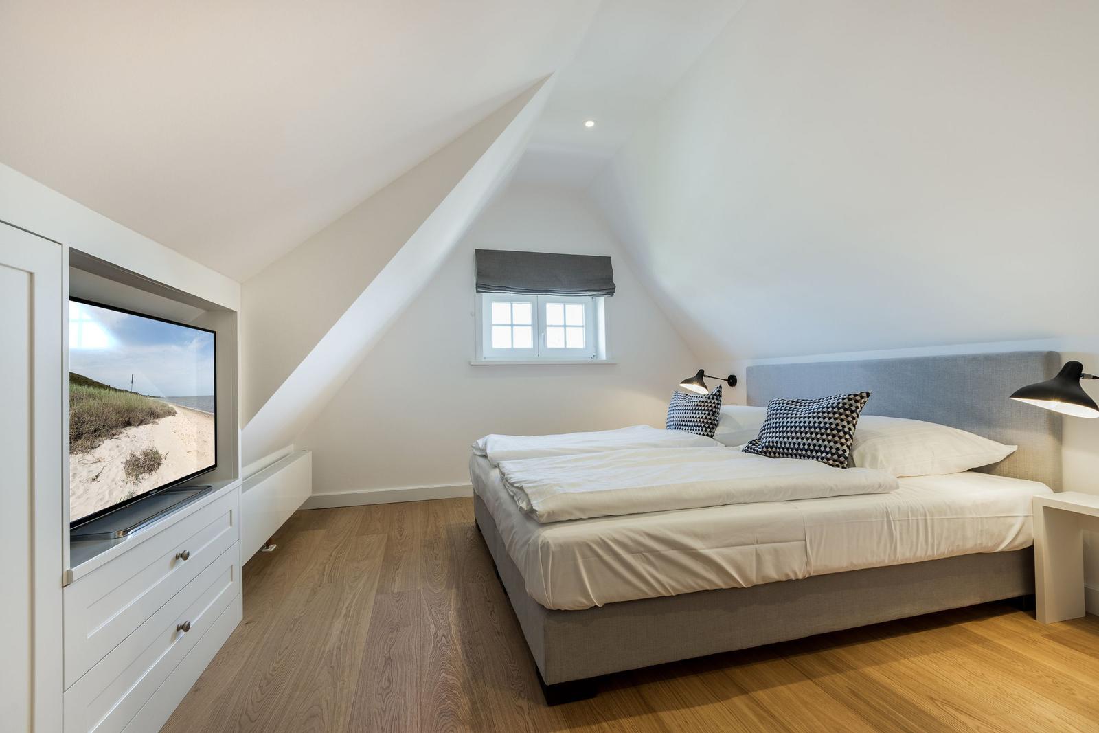 Bedroom with sloped ceiling, bed, window, and TV.