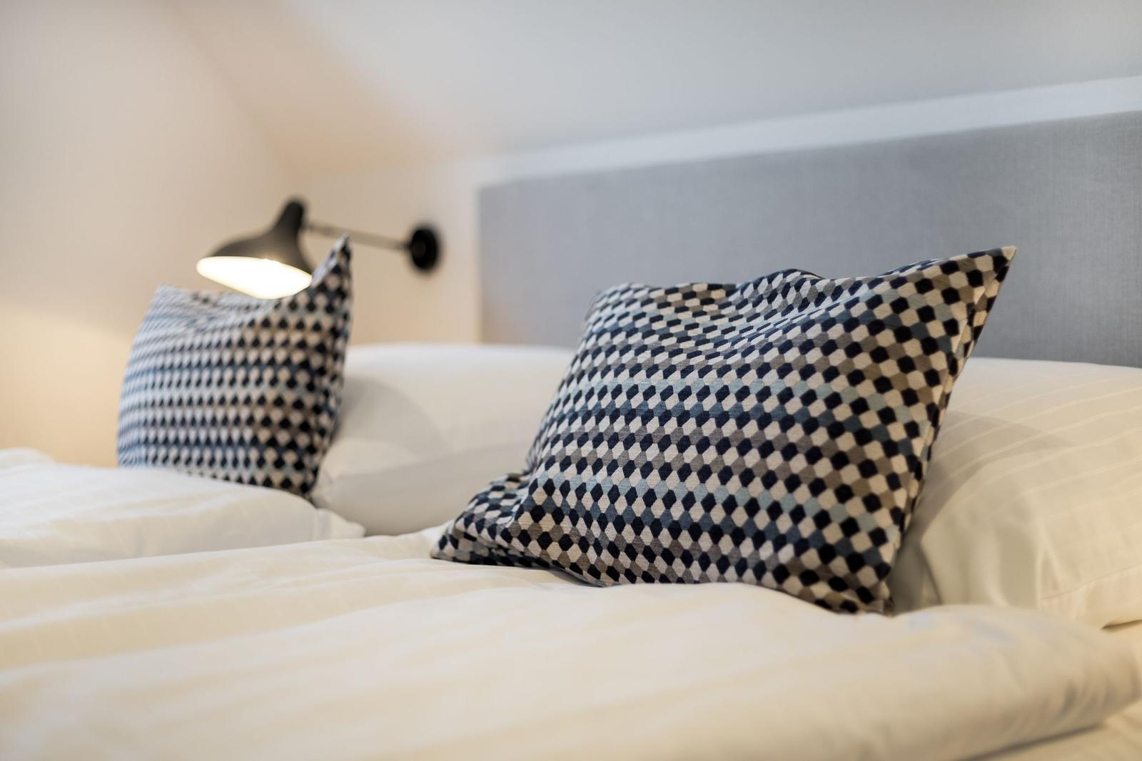 A bed with pillows and a wall lamp