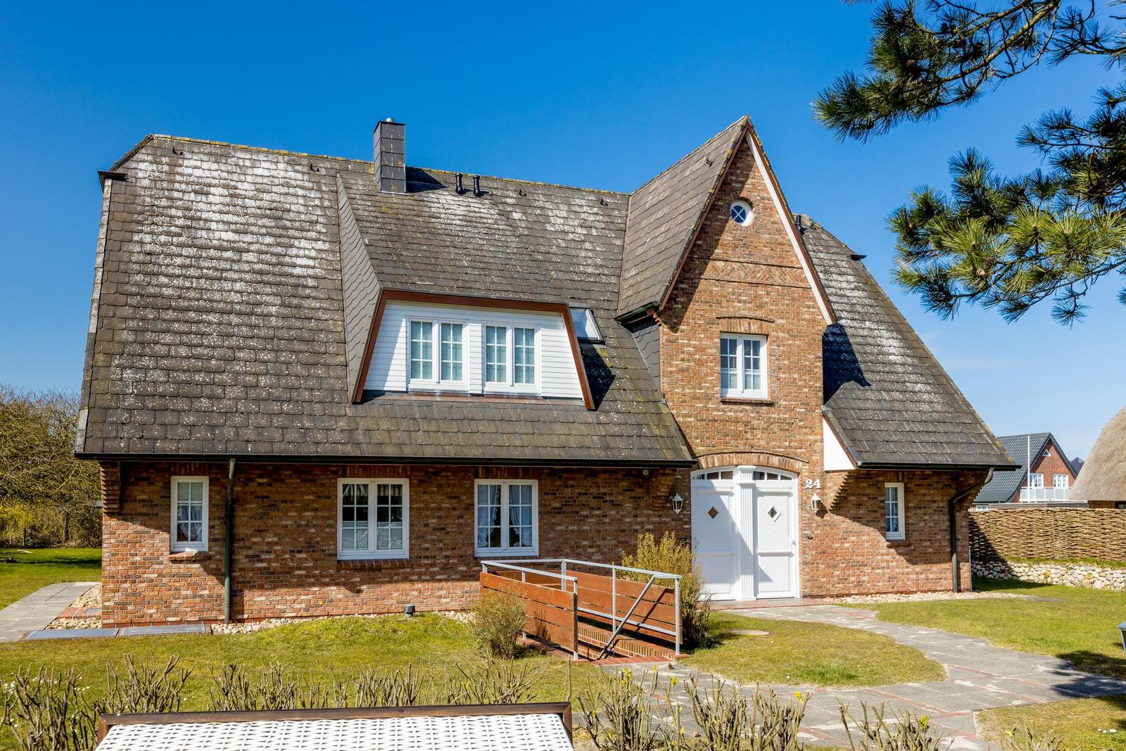 House with red brick, black roof, and white door