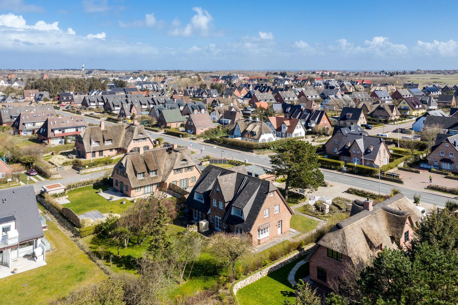 Aerial view of a village with traditional houses and green lawns.