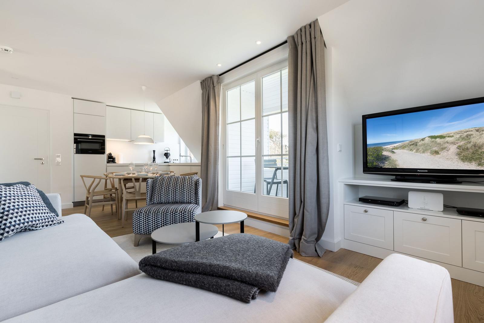 Living area with sofa, TV, and view of balcony.