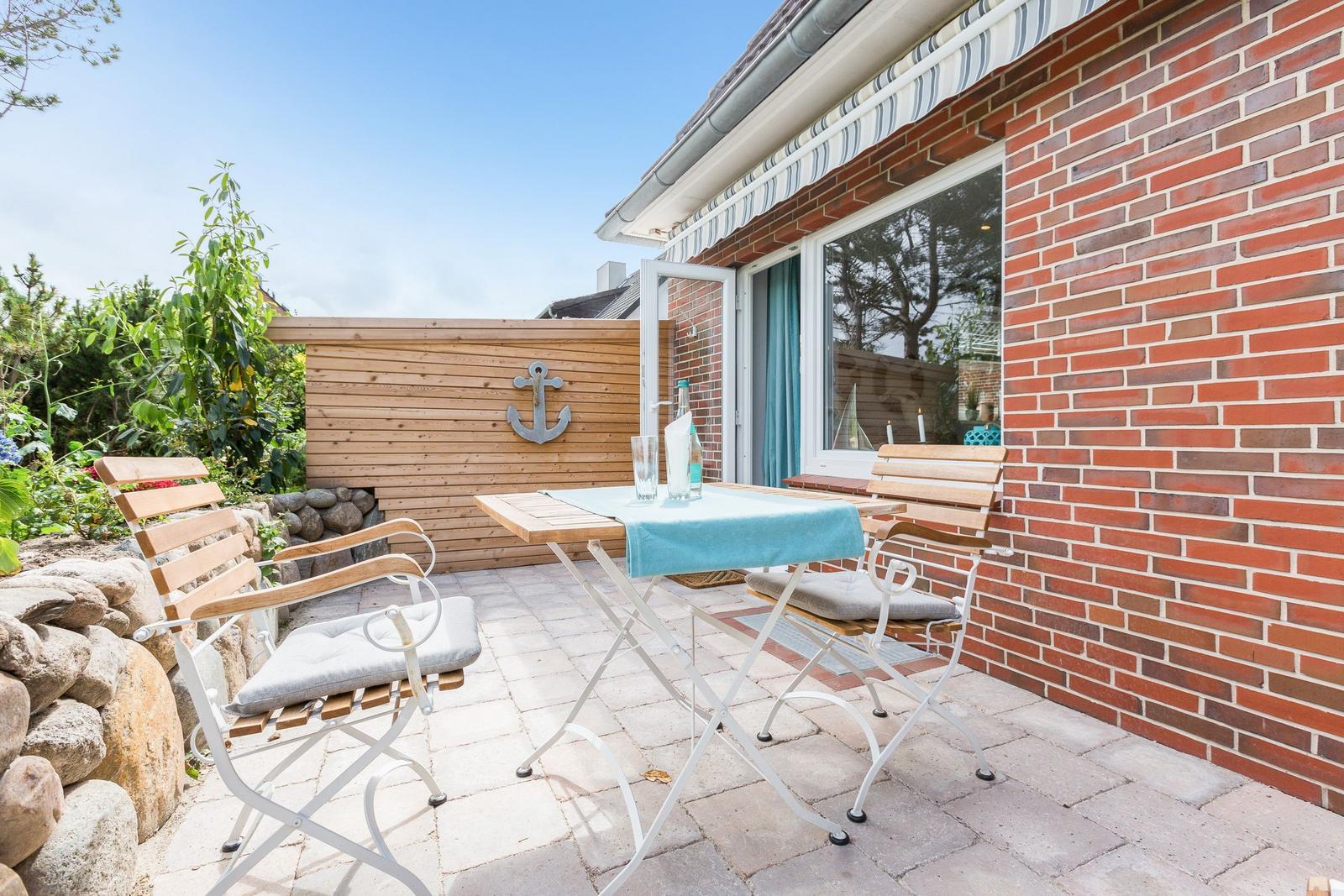 Terrace with table, chairs, and anchor on wooden wall.