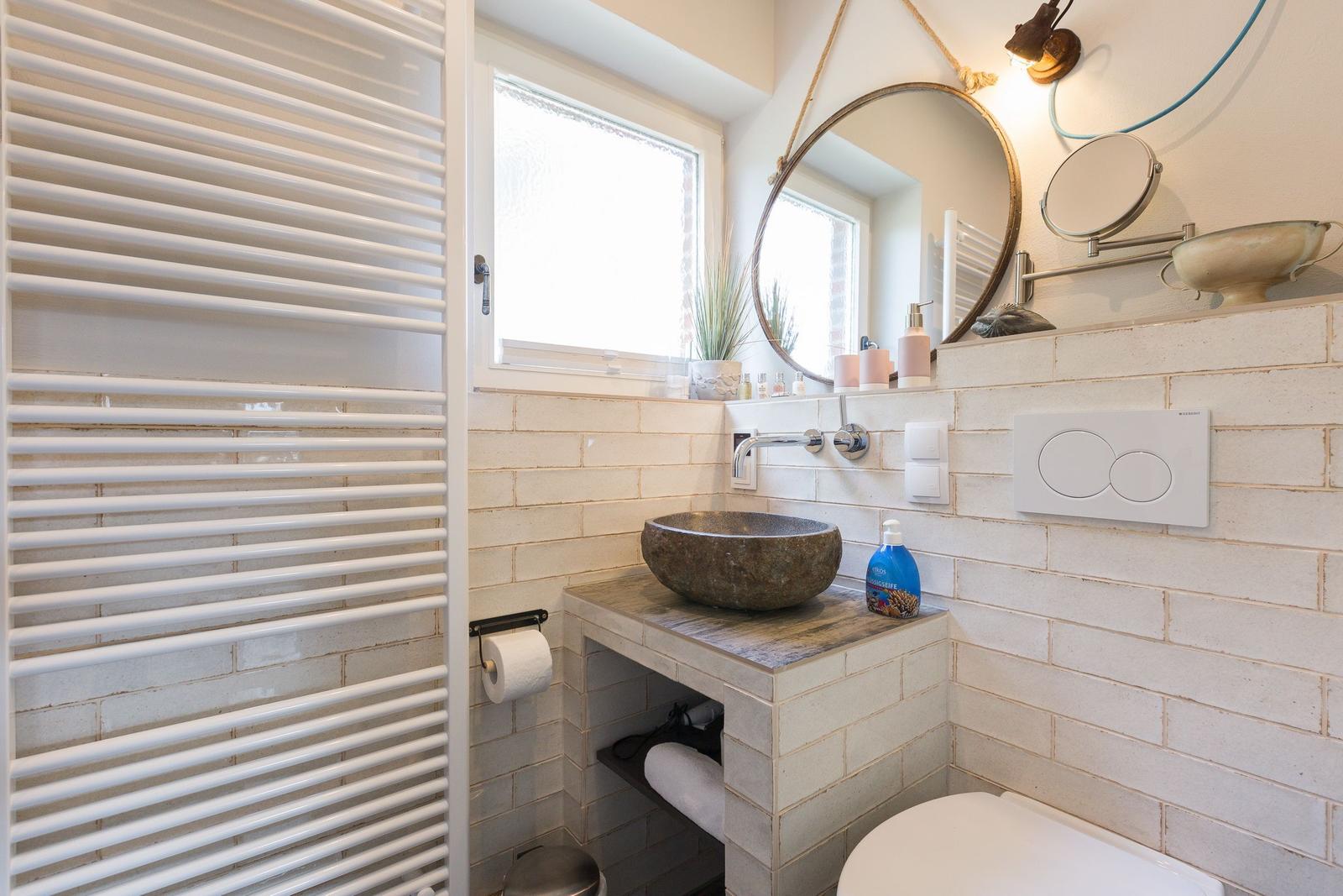 Bathroom with stone sink, mirror, and radiator.