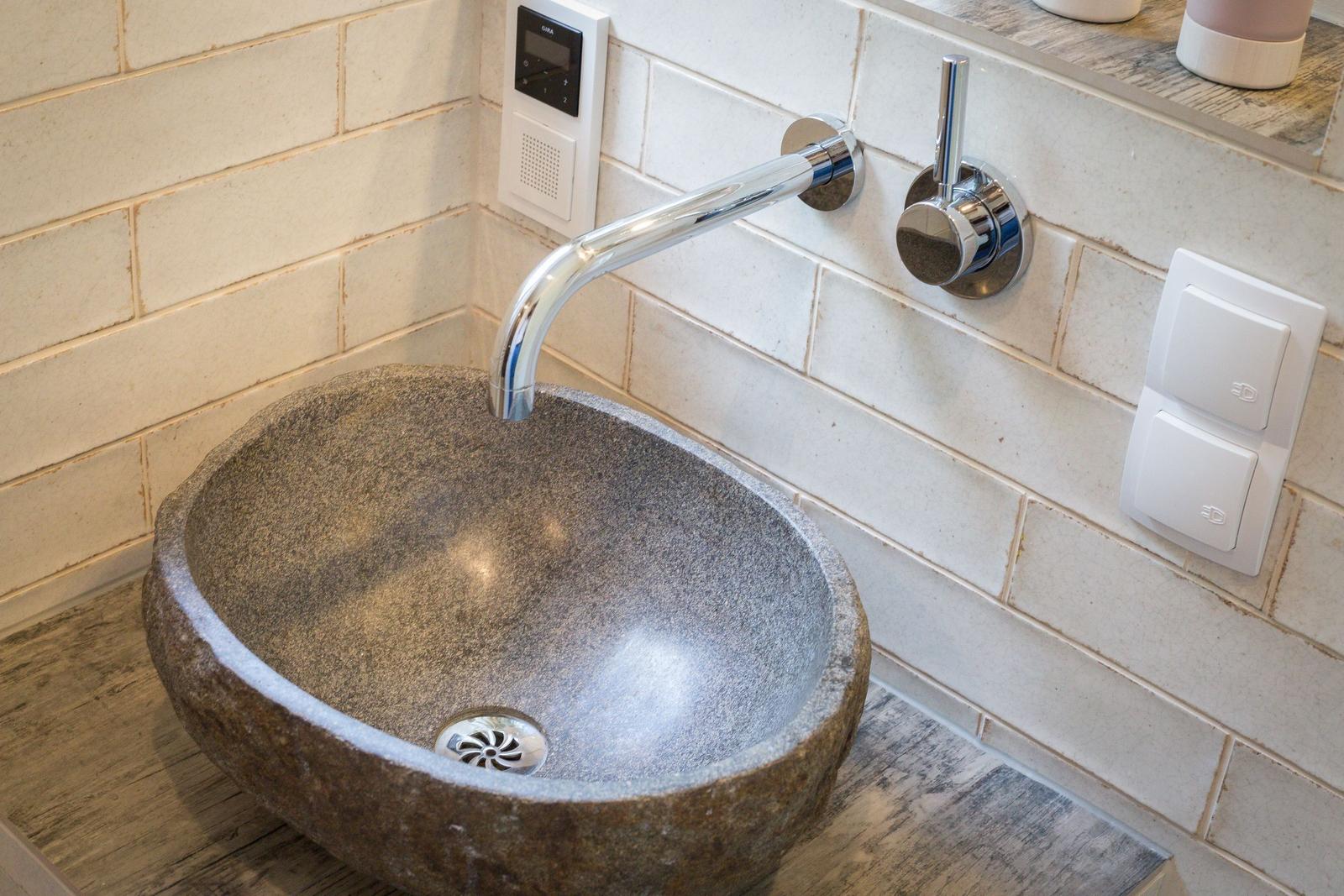 Stone sink with faucet and wall-mounted control