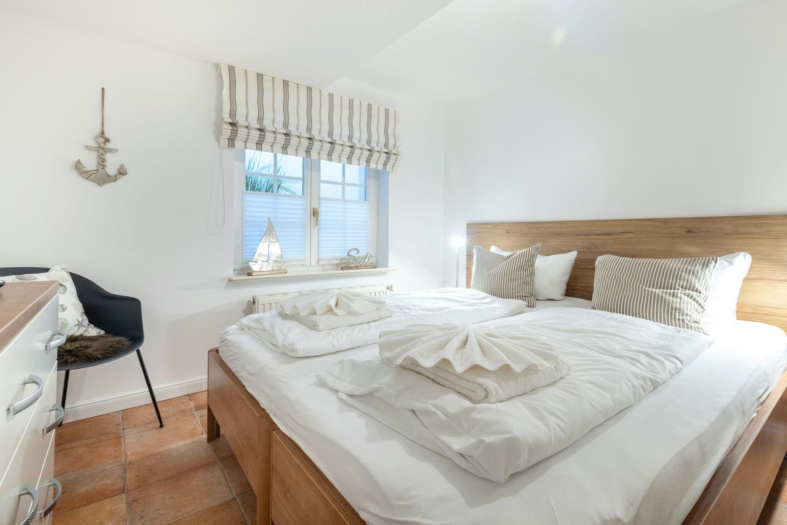 Bedroom with double bed, wooden frame, window, and anchor decoration.