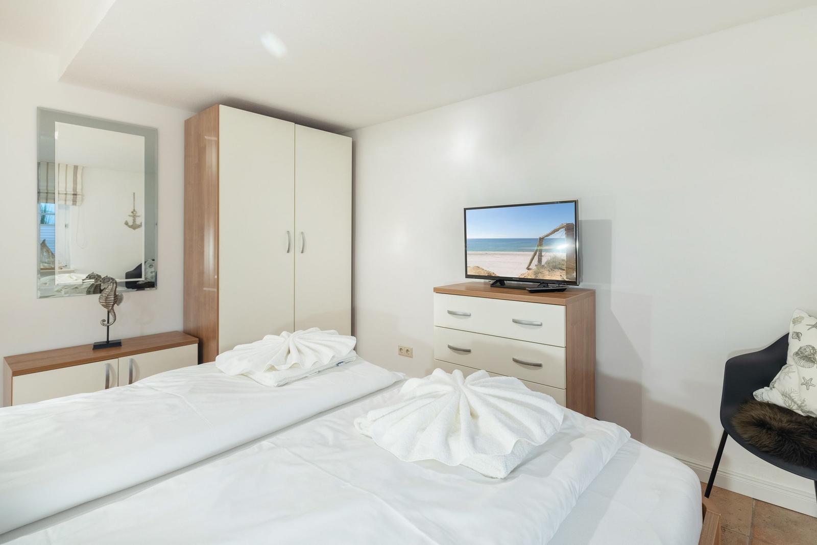 Bedroom with bed, wardrobe, TV, and mirror.