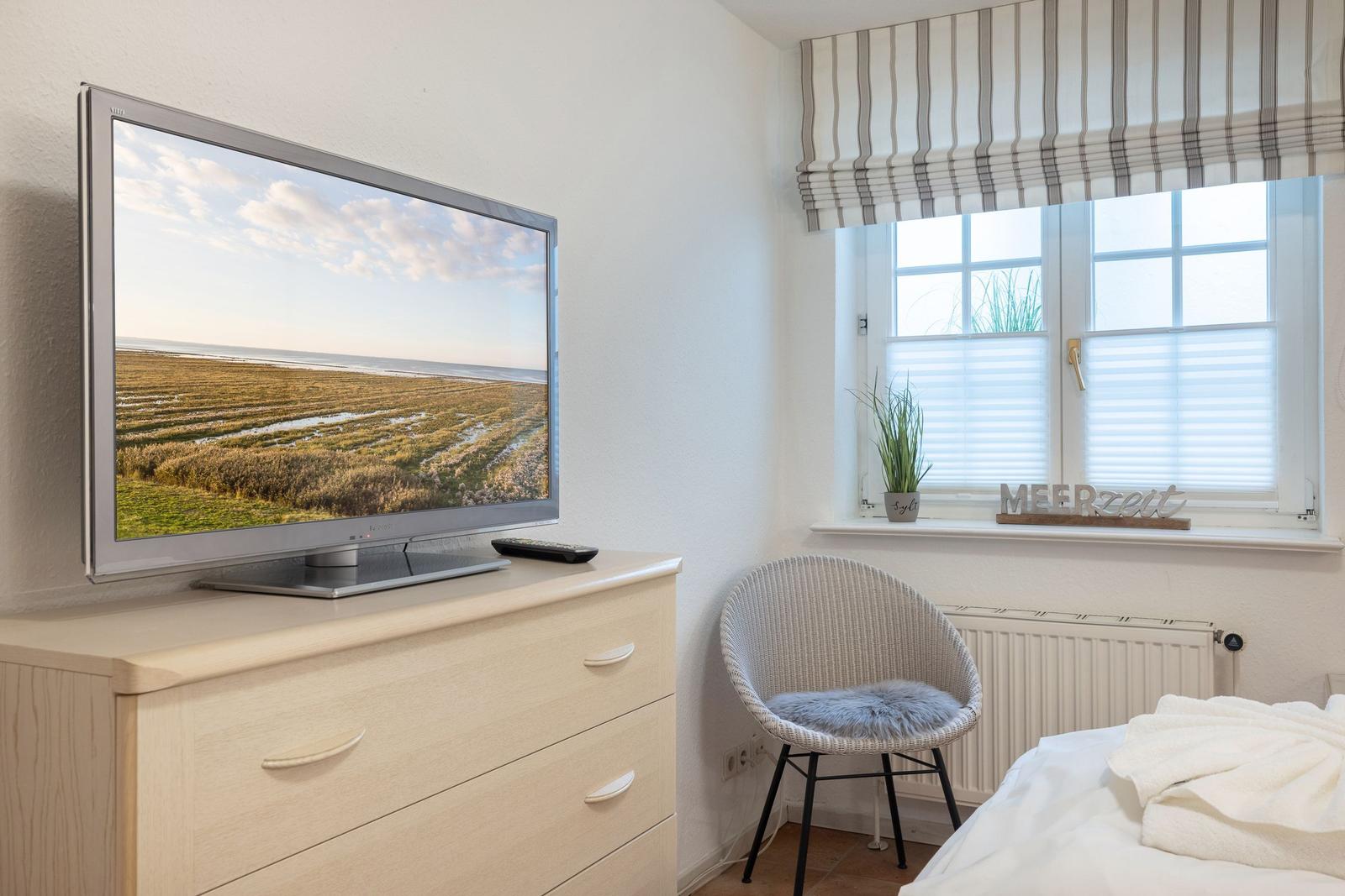 Bedroom with TV, chair, and window with blinds.