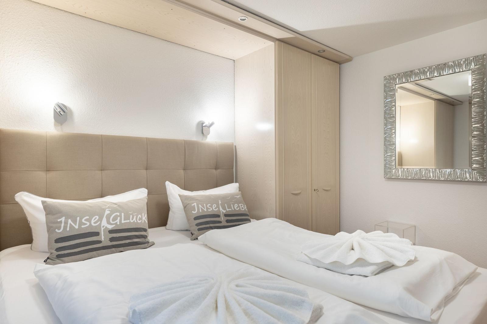 Bedroom with double bed, wardrobe, and mirror on the wall.