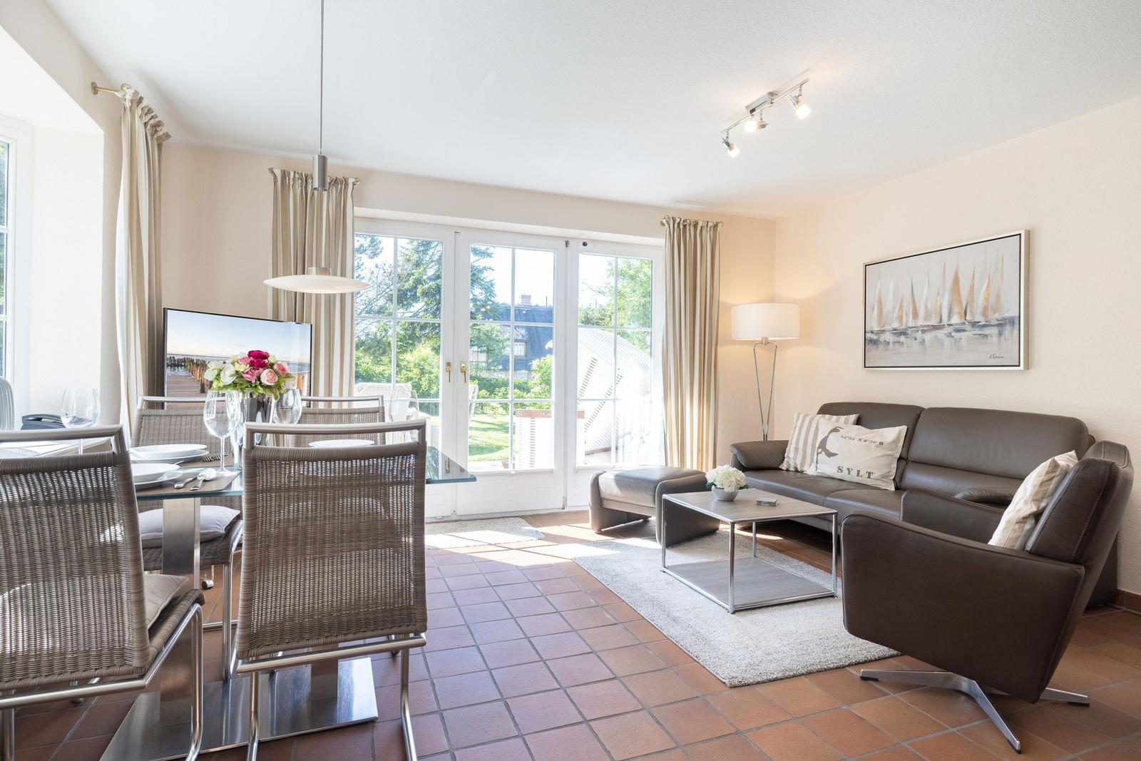 Living and dining area with sofa, dining table, and garden view.