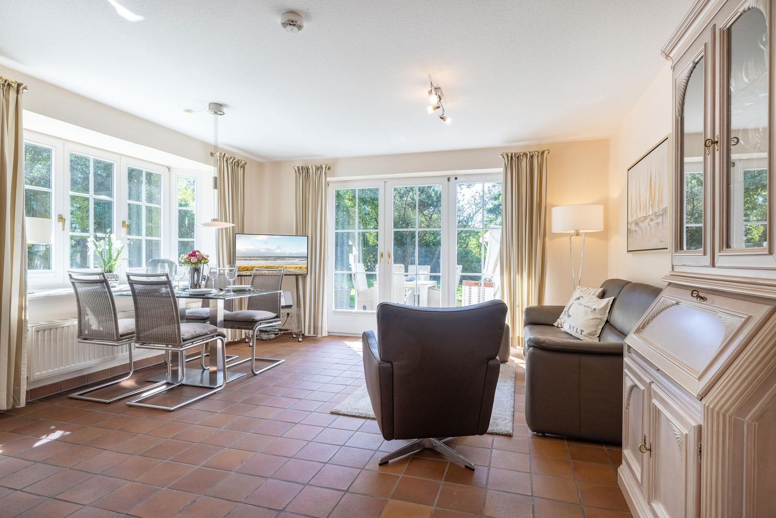 Living and dining area with terrace door, sofa, armchair, and dining table.