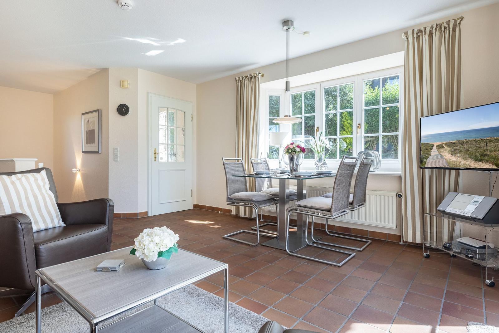 Living and dining area with terracotta floor, glass furniture, and TV.
