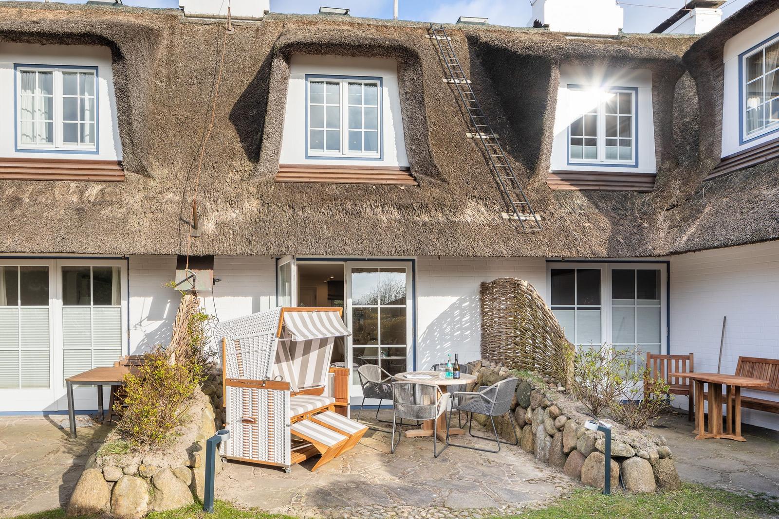 House with thatched roof, terrace with lounge chair and table
