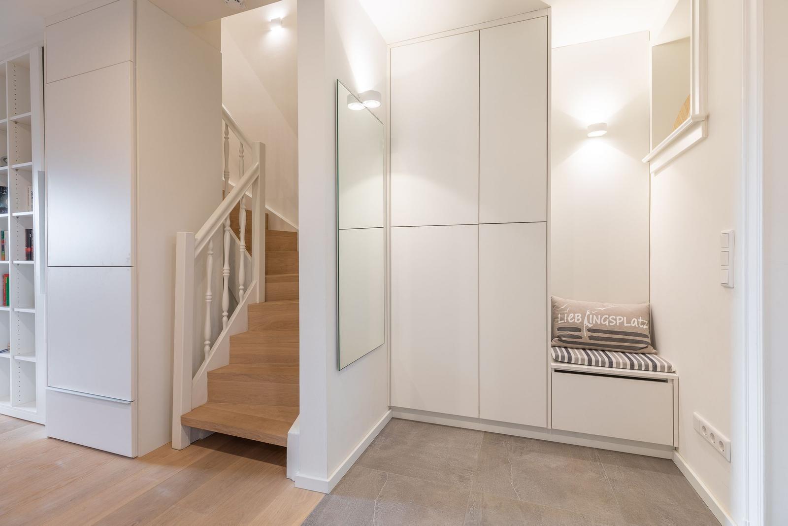 Entrance area with stairs, mirror, and seat with cushion.