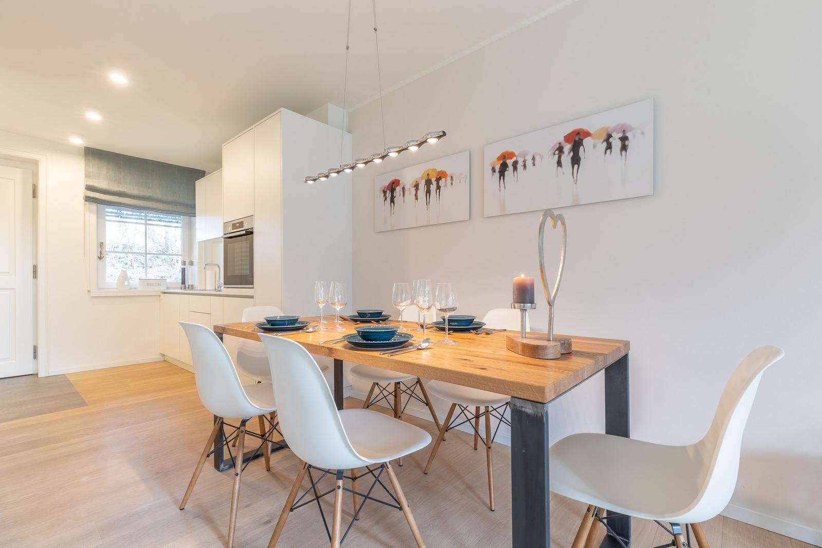 Dining area with wooden table, white chairs, and wall art