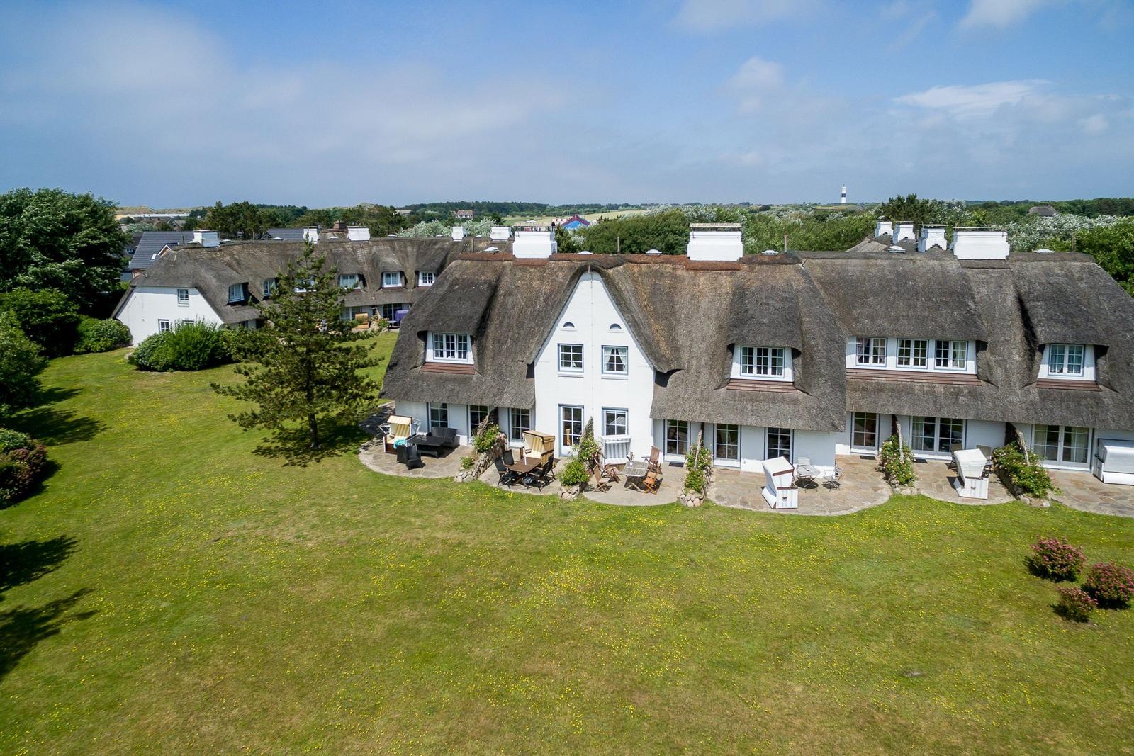 House with thatched roof and large garden. Outdoor seating area.