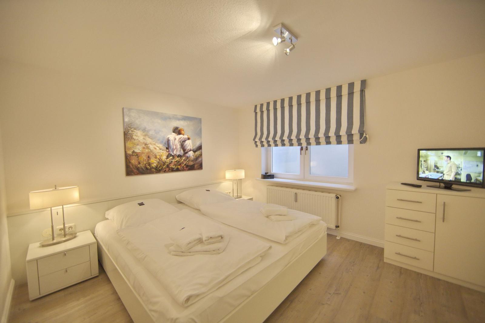 Bedroom with double bed, window, TV, and nightstand.