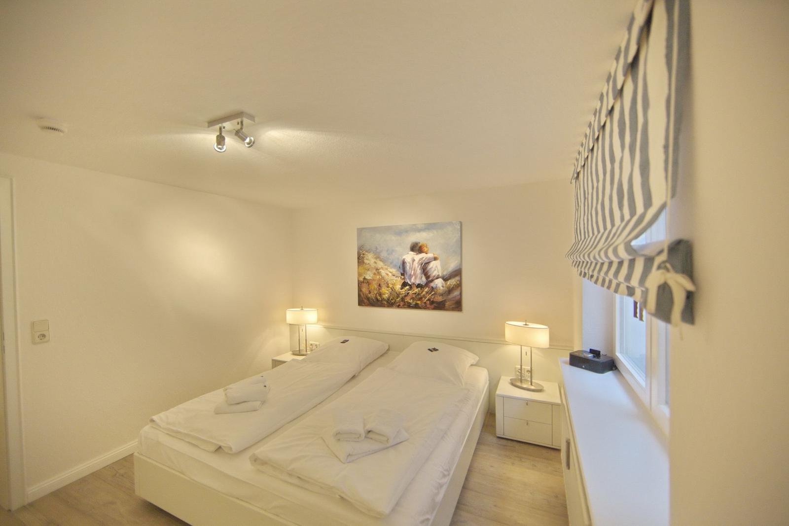 Bedroom with double bed, two nightstands, and wall art.