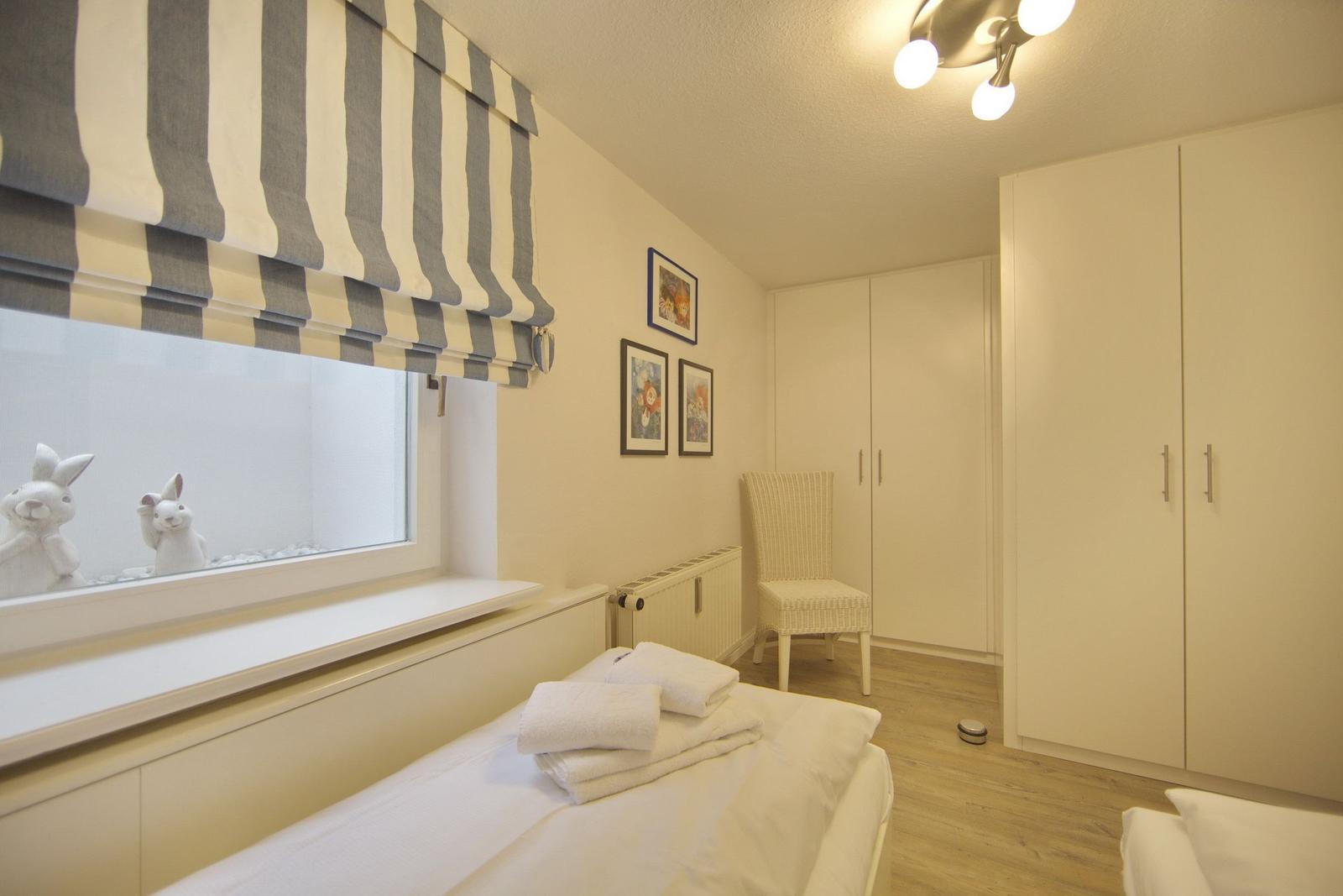 Bedroom with bed, wardrobe, and window with curtain.