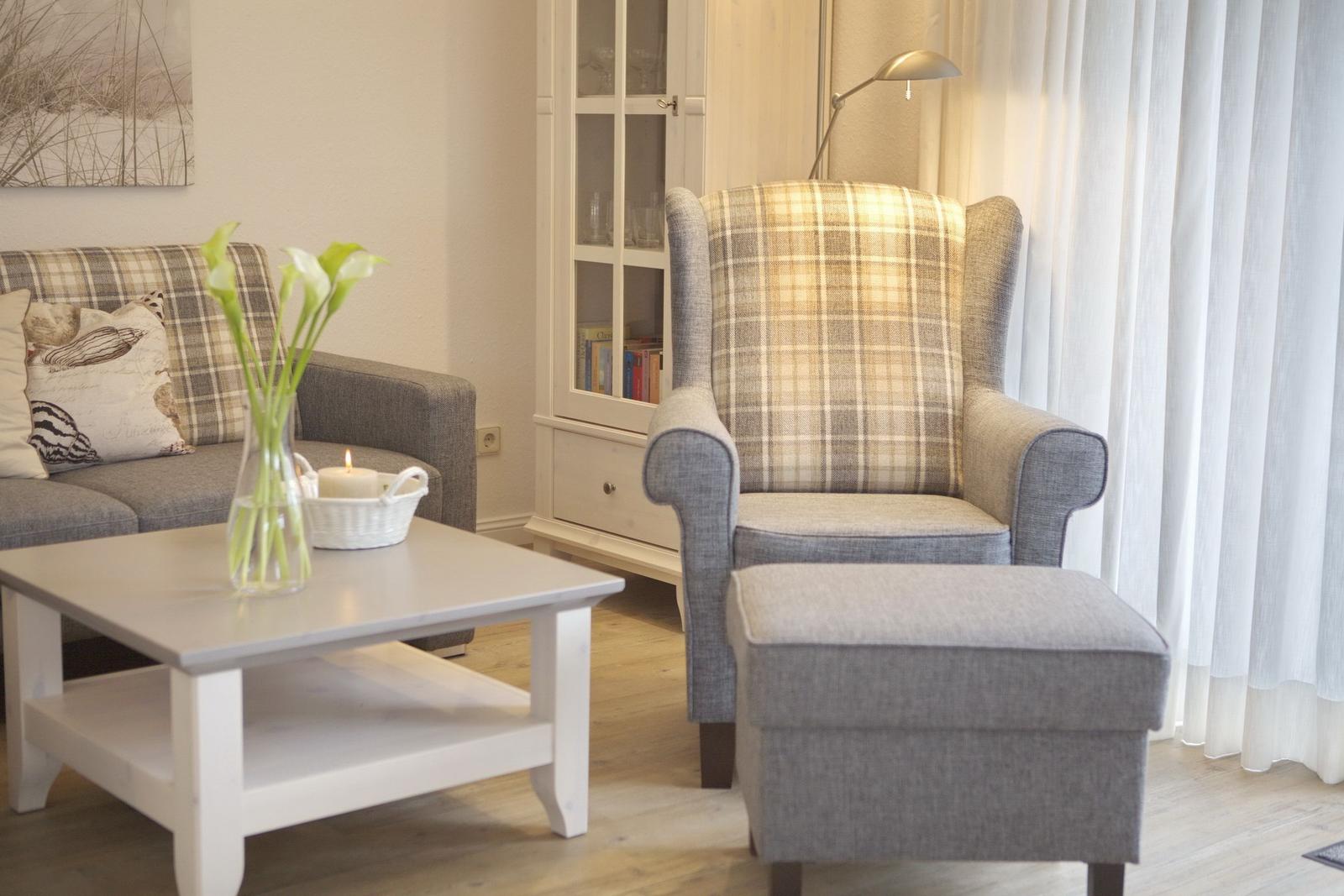 Living room with armchair, sofa, table, and curtains.