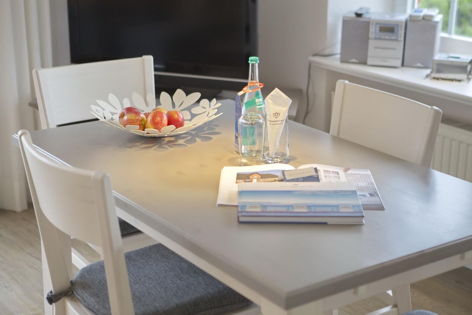 Dining table with chairs, fruit bowl, and water bottles.
