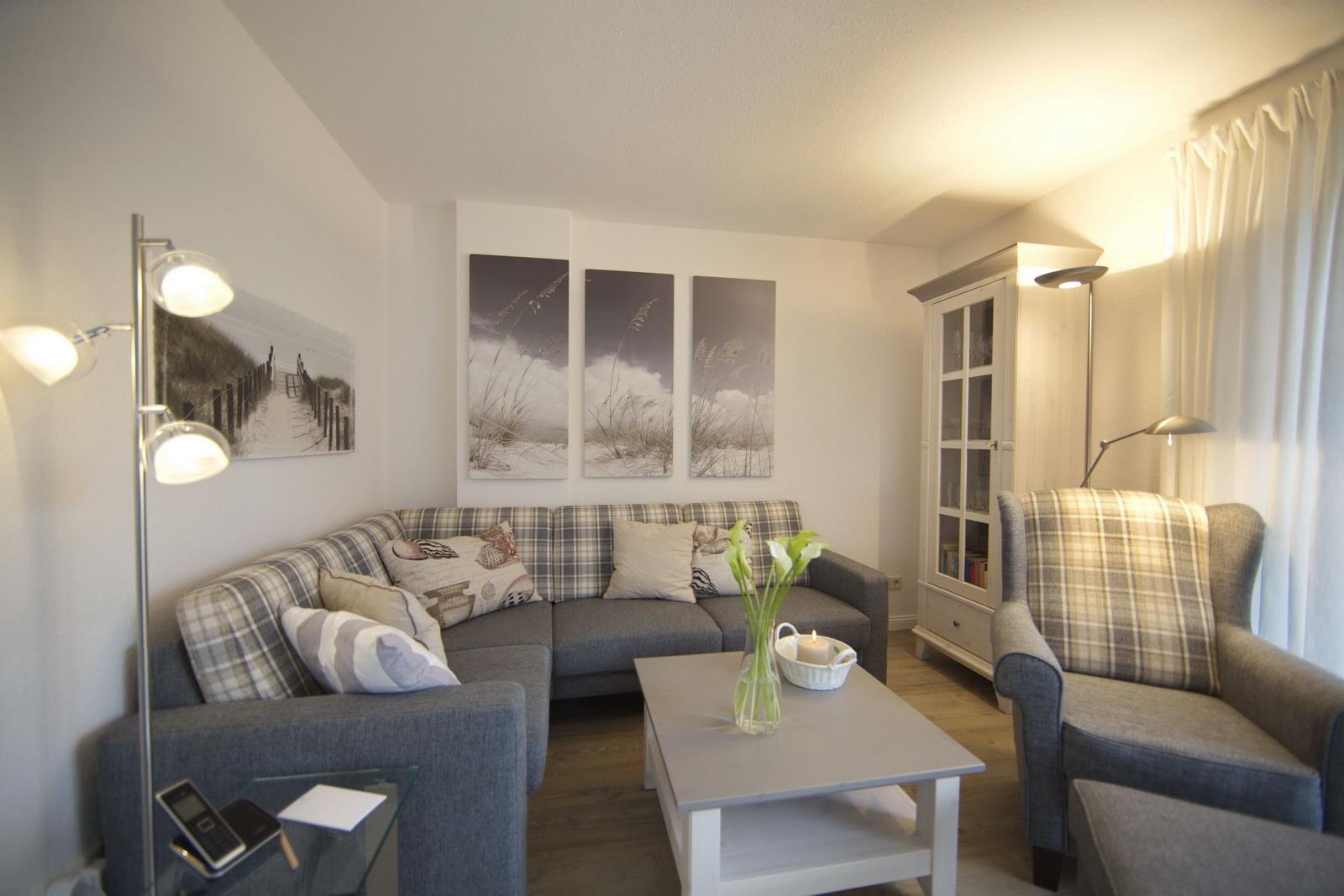 Living room with sofa, armchair, and table. Pictures hang on the walls.