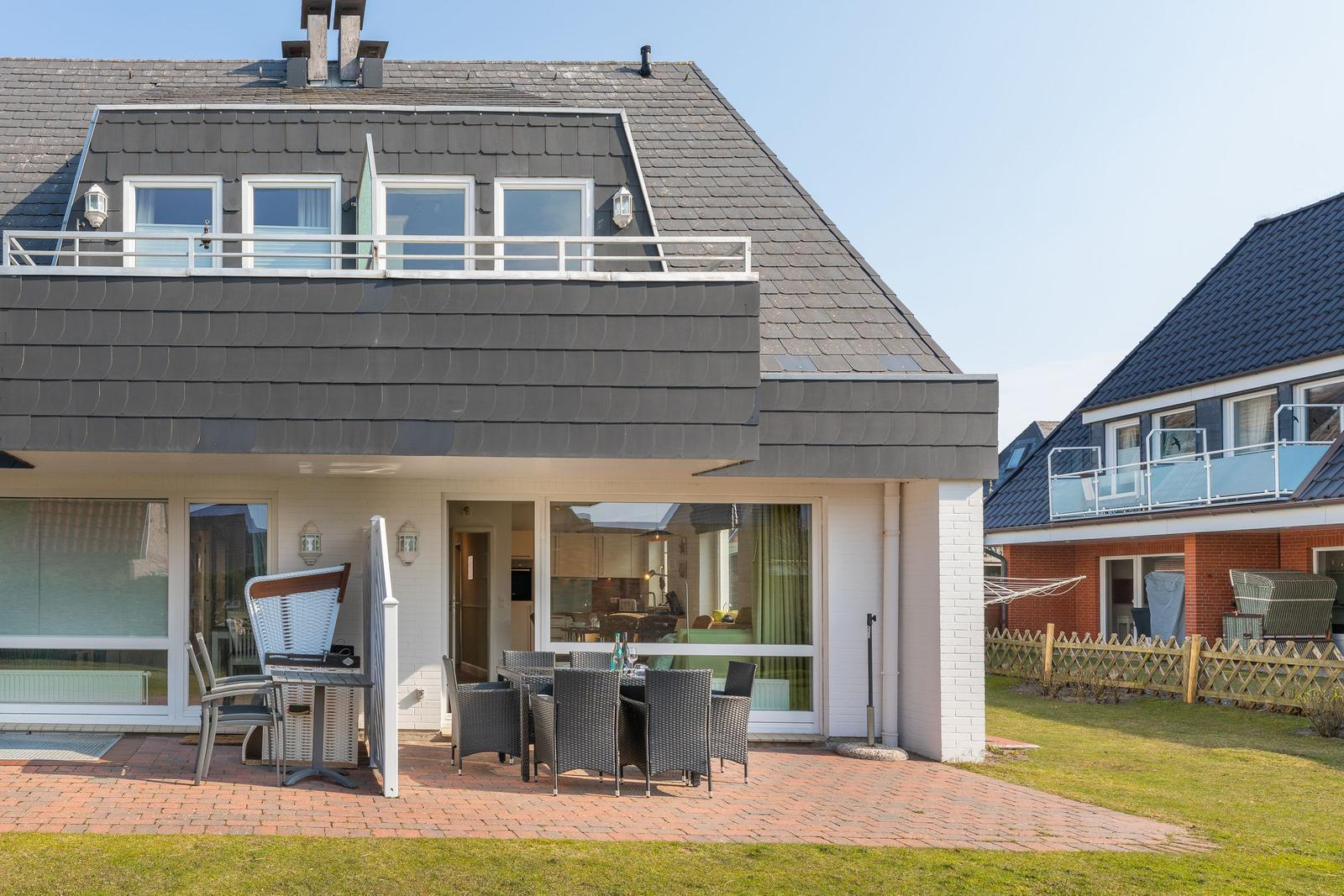 Haus mit Terrasse, Grill und Sitzgelegenheiten im Freien.