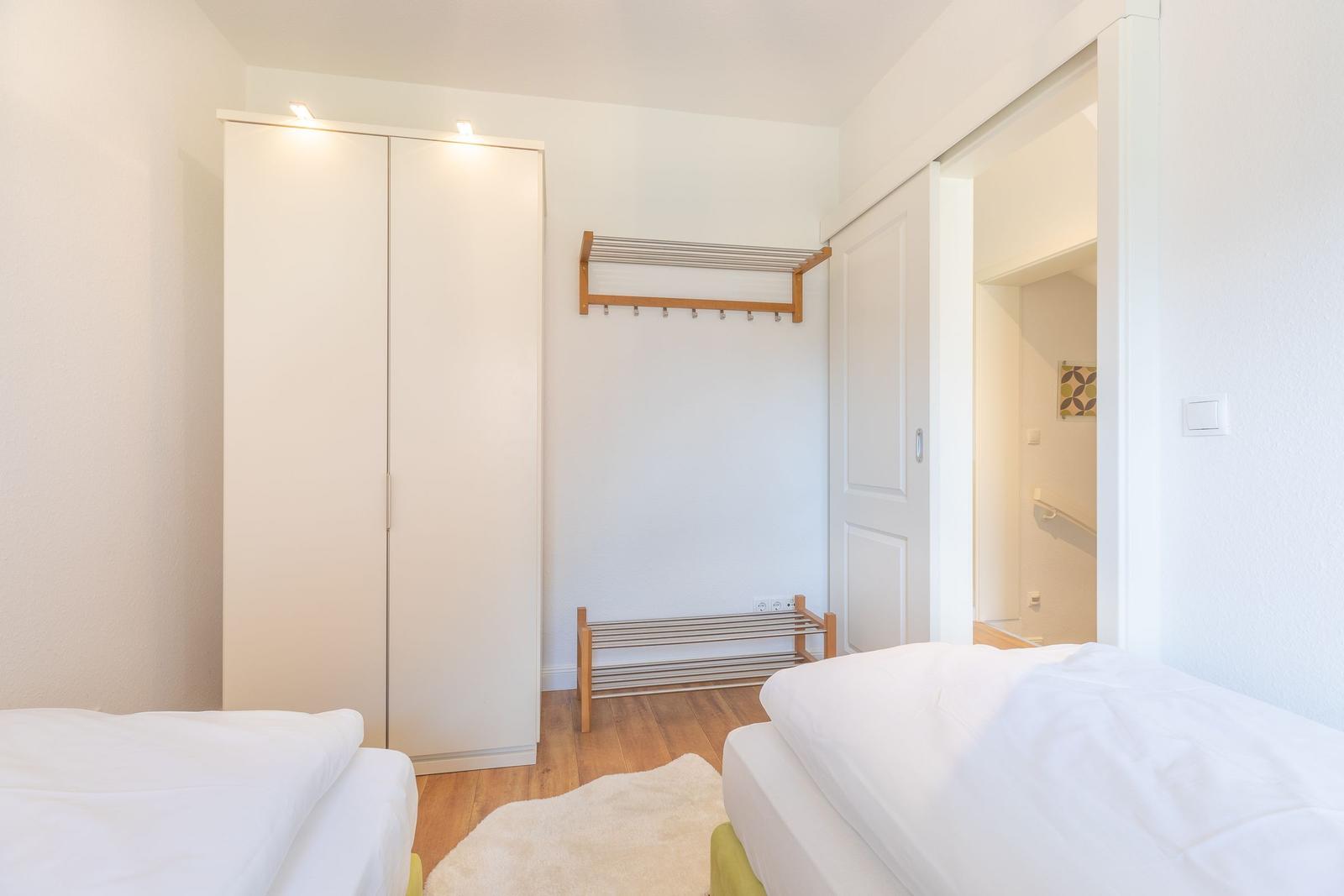 Zwei Betten, Kleidergarderobe und Hängeregler im Schlafzimmer.