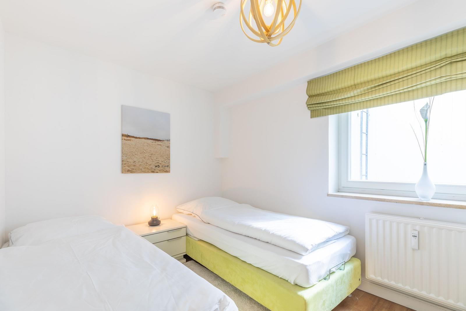 Zwei Betten, Fenster mit Rollladen und Wandbild.