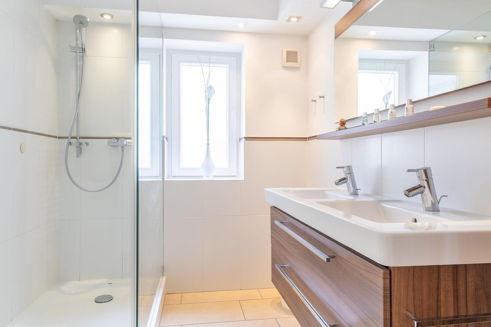 Badezimmer mit Dusche, Waschbecken und Fenster