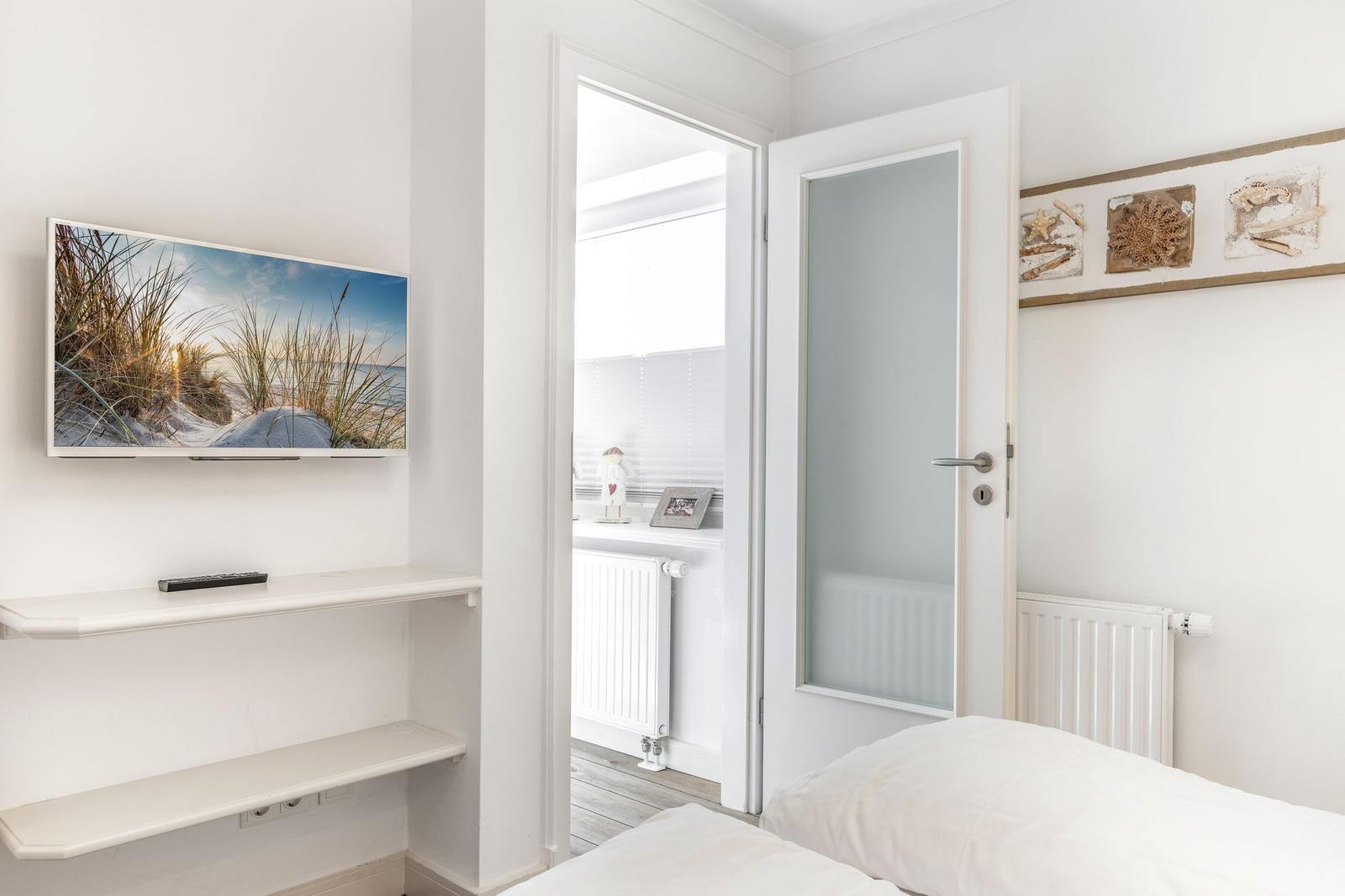 Bedroom with bed, TV, and door to bathroom.