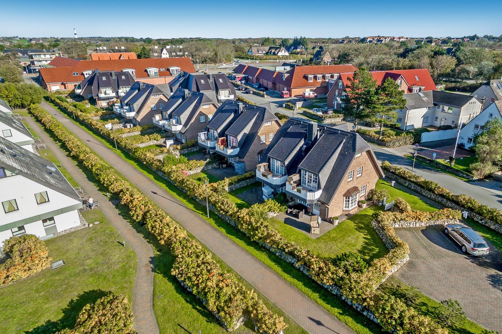 Aerial view of residential houses with gardens and a paved path.