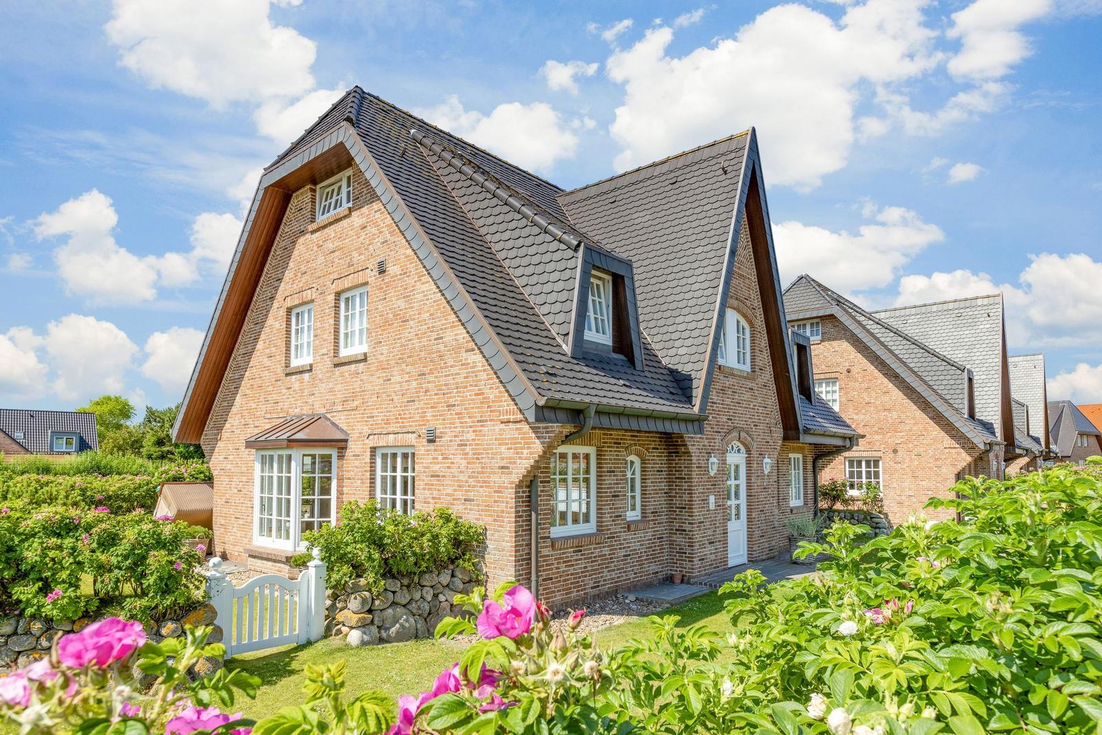 A two-story house with brick facade and black roof under blue sky.