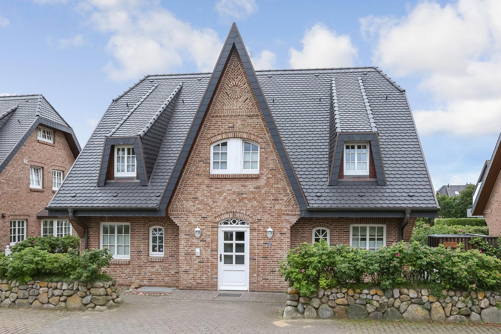 Haus mit Ziegelfassade und schwarzem Satteldach mit Dachfenstern.