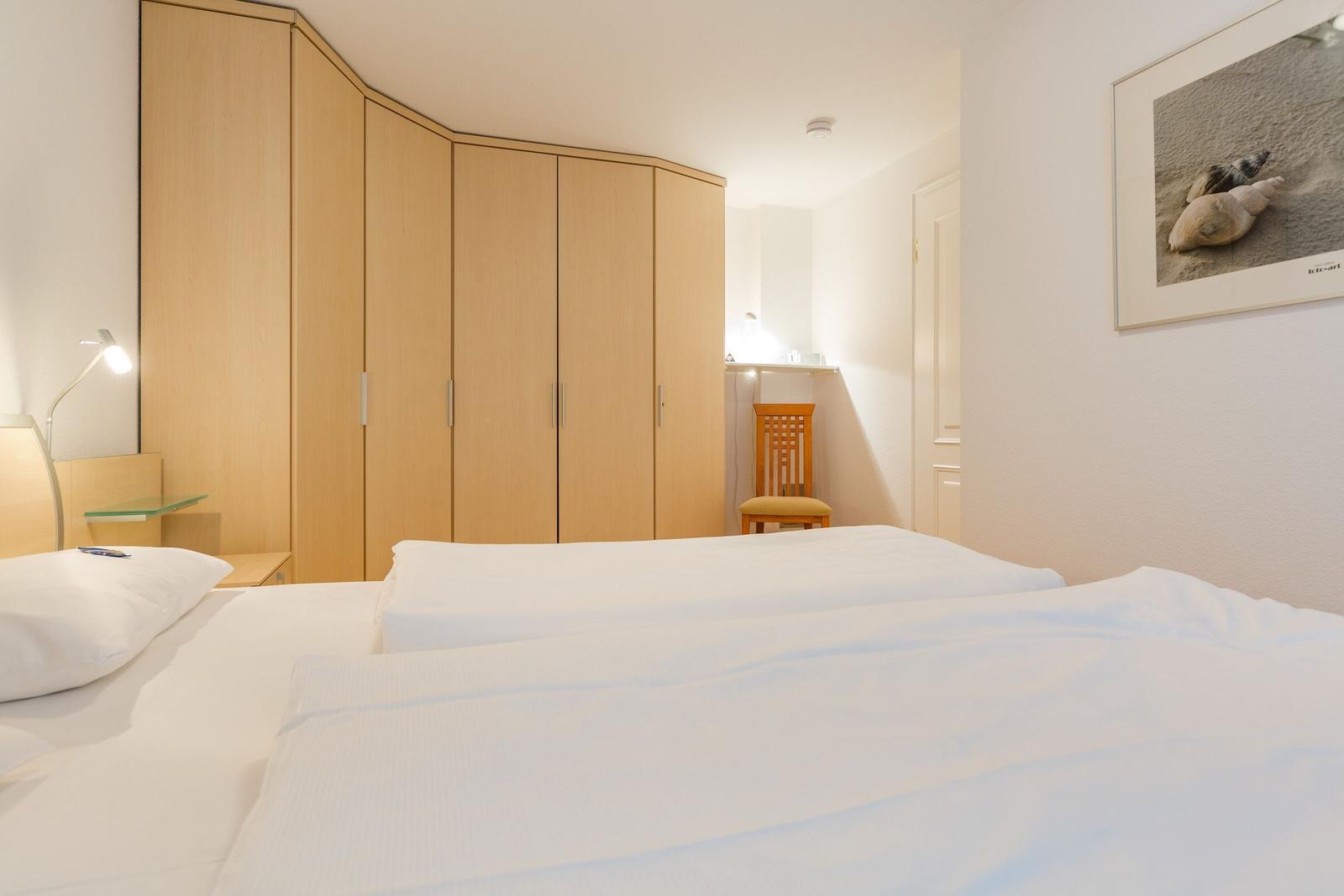 Schlafzimmer mit Bett, Kleiderschrank und Stuhl.