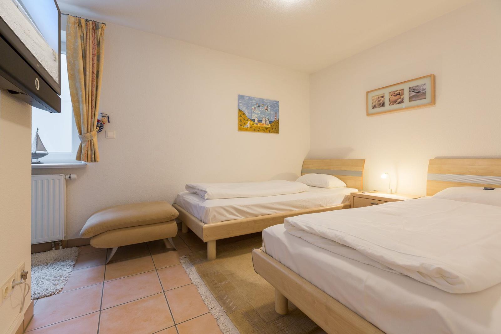 Zwei Betten mit weißen Bettwäsche, Holzgestell, Nachttisch und Wandbild.